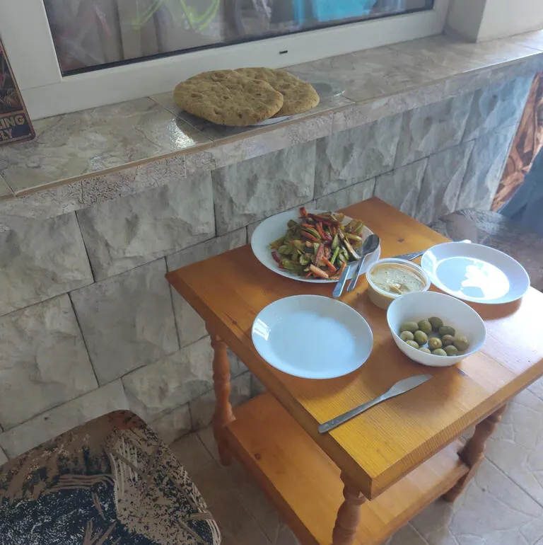 Ein kleiner Tisch und zwei Hocker vor unser Unterkunft in Pomorie. Darauf steht gebratenes Gemüse für das Abendbrot.