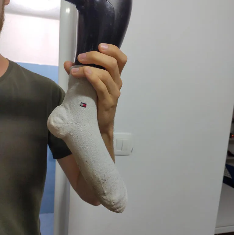 Tim, der eine über einen Föhn gezogene Socke trockenföhnt.
