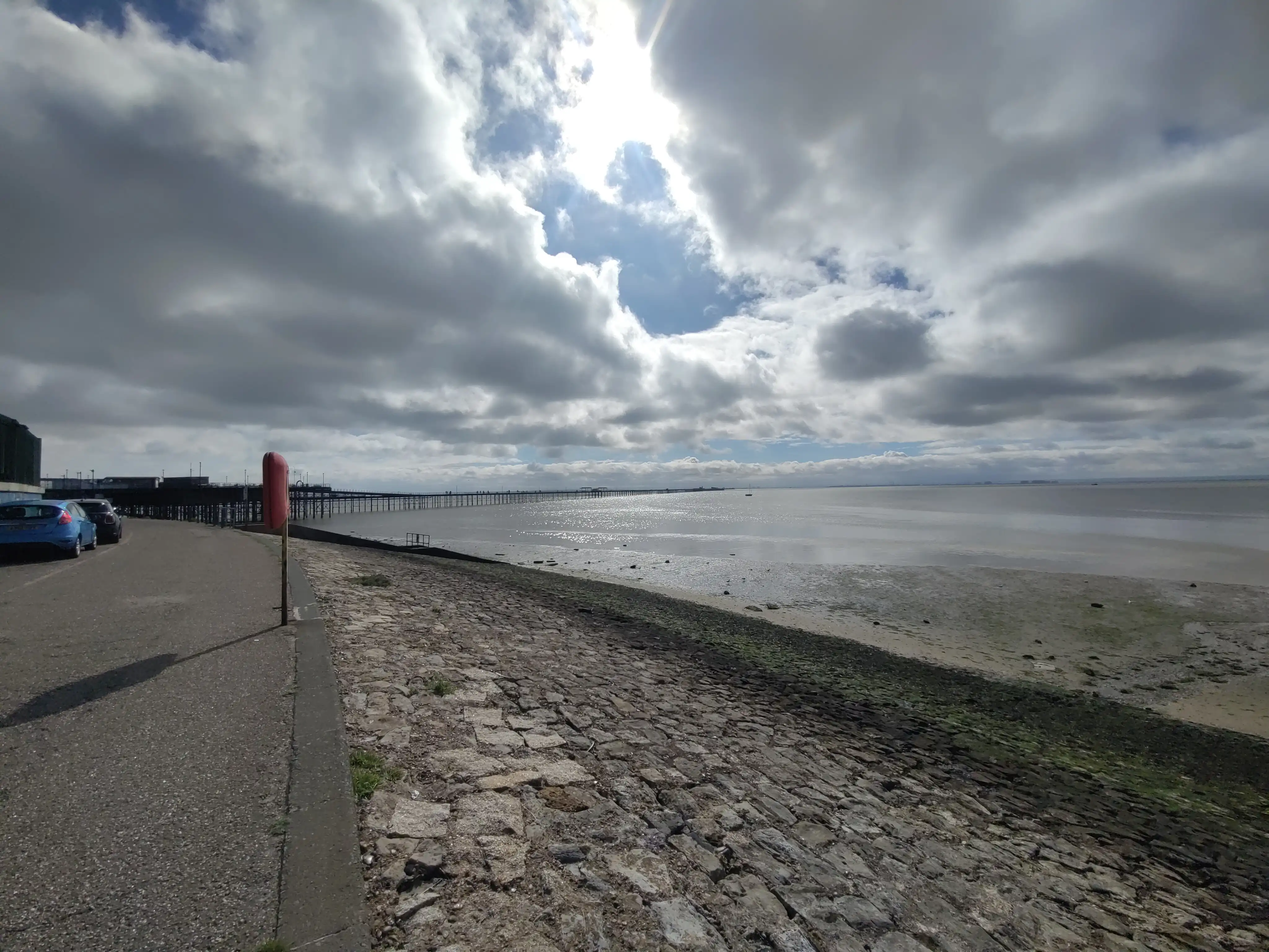 Blick auf den Besuchersteg von Southend. Wegen der Ebbe sieht man eine weite Wattenlandschaft und ein kleines, trocken liegendes, Boot.