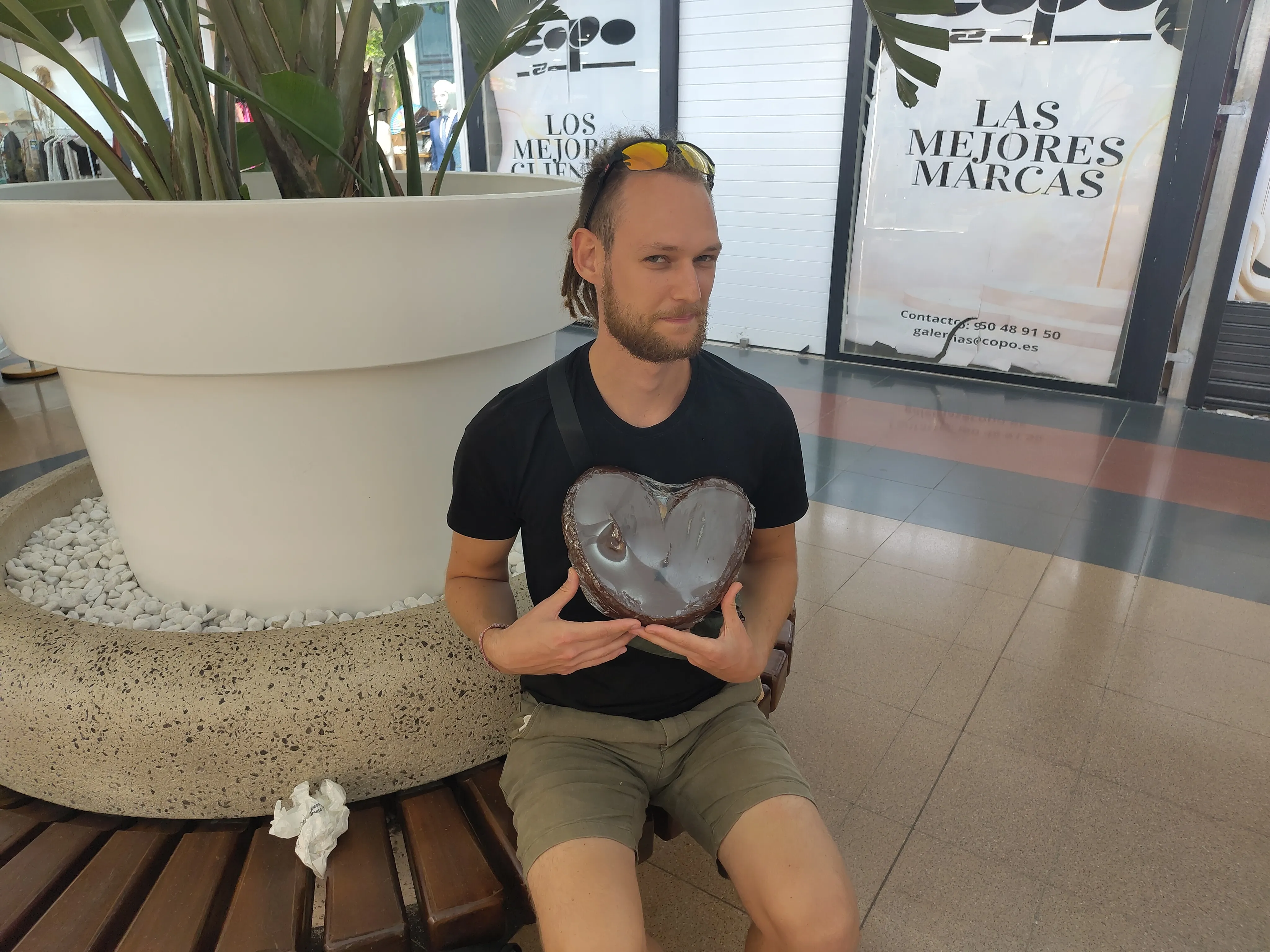 Tim, auf einer Bank im Einkaufszentrum, mit einem sehr großen Schweineohr in der Hand.