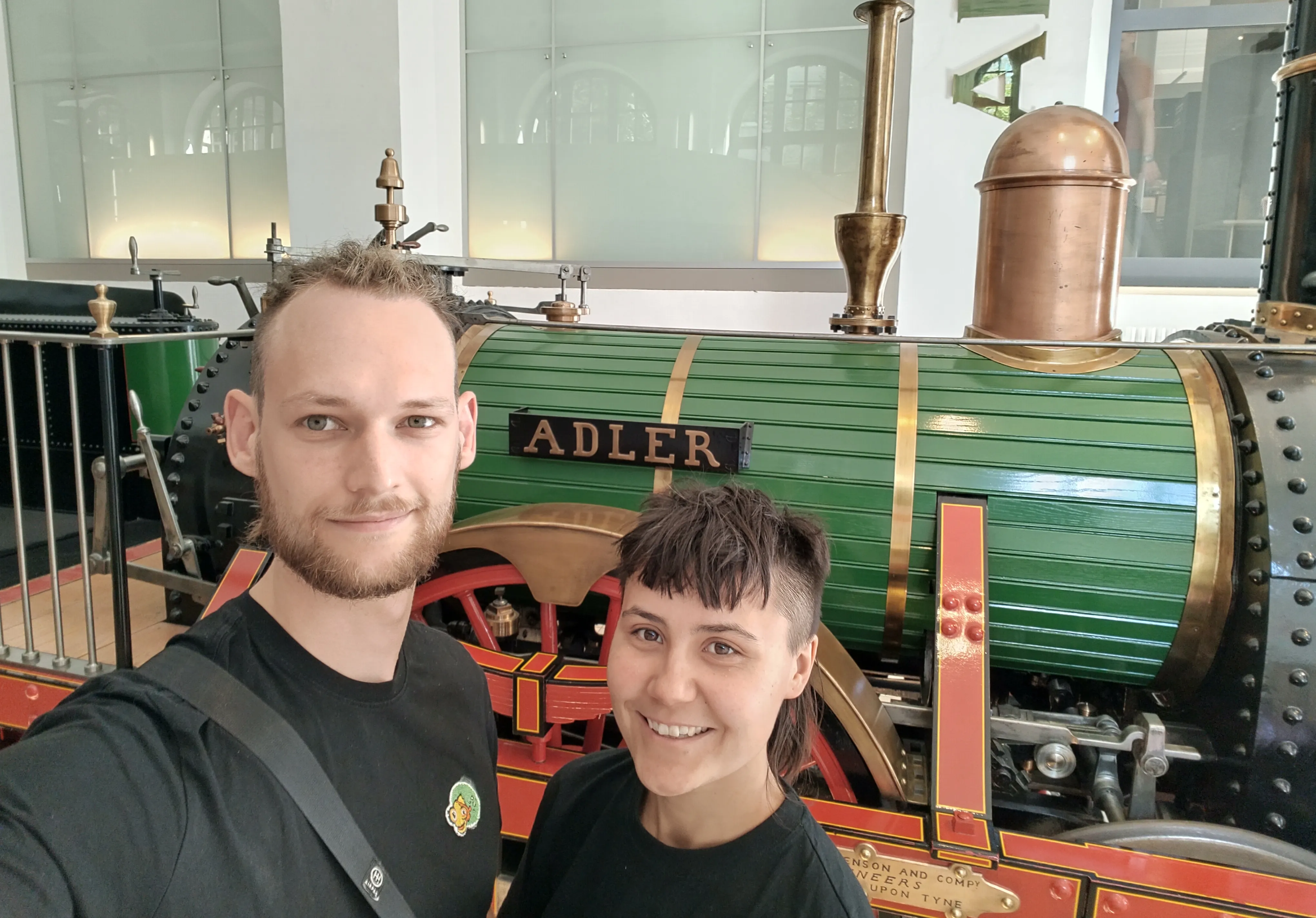 Chiara und Tim stehen vor einer Lokomotive Modell Adler.